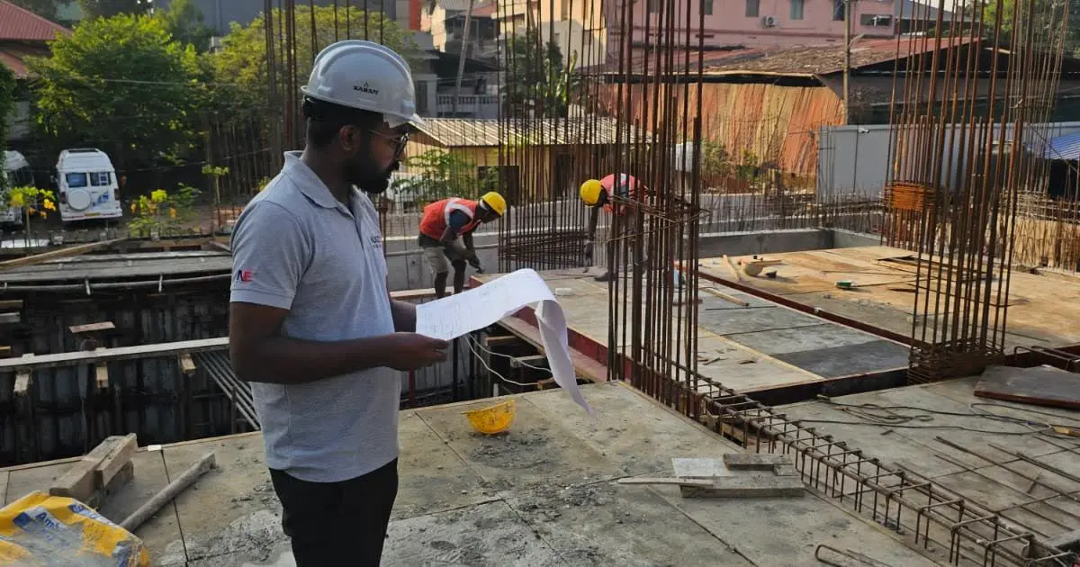 An Augzet engineer on site in a hard hat, checking the installation against the drawing set.